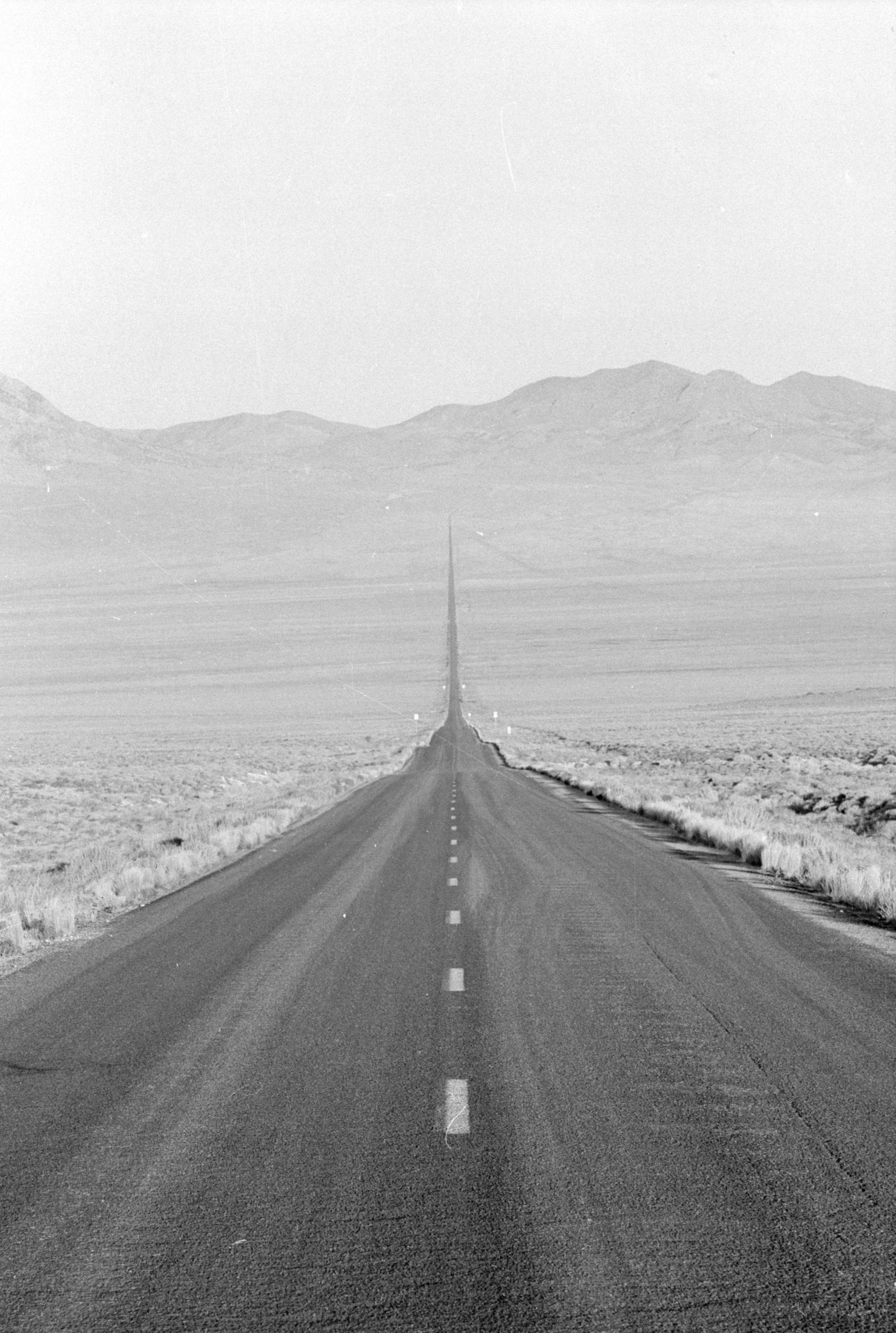 a long empty road stretches into mountains in the distance