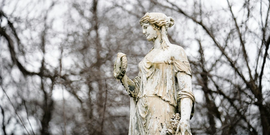 a statue of a person with an owl in a park