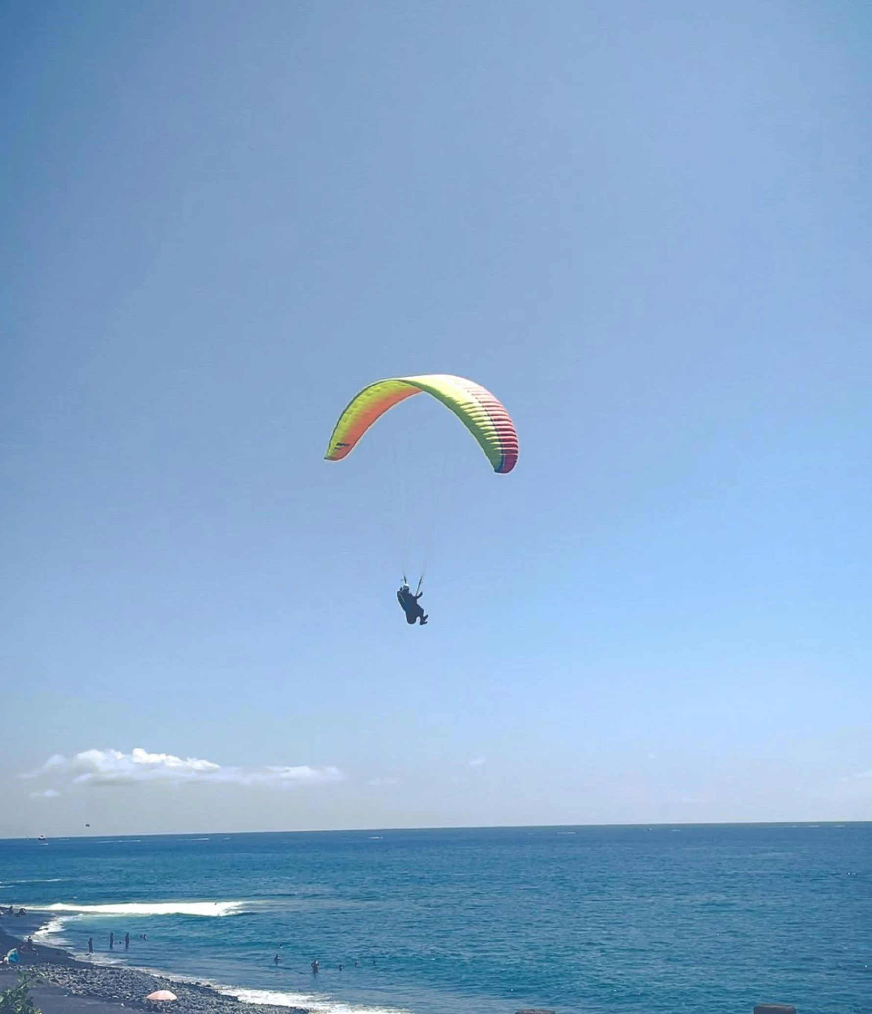 paraglider in motion over the ocean on the clear day