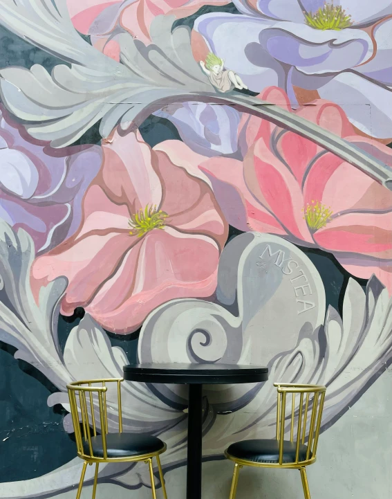 two chairs are facing a painting of flowers on a wall