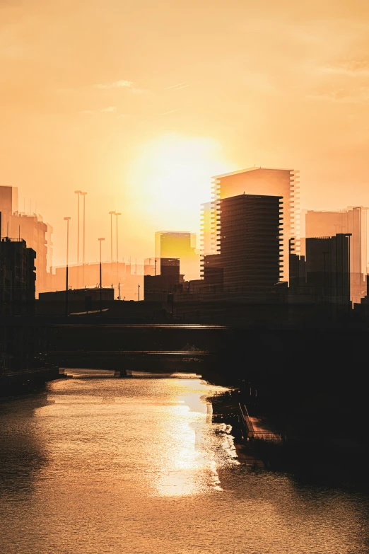 a sunset view of some tall buildings from across the water