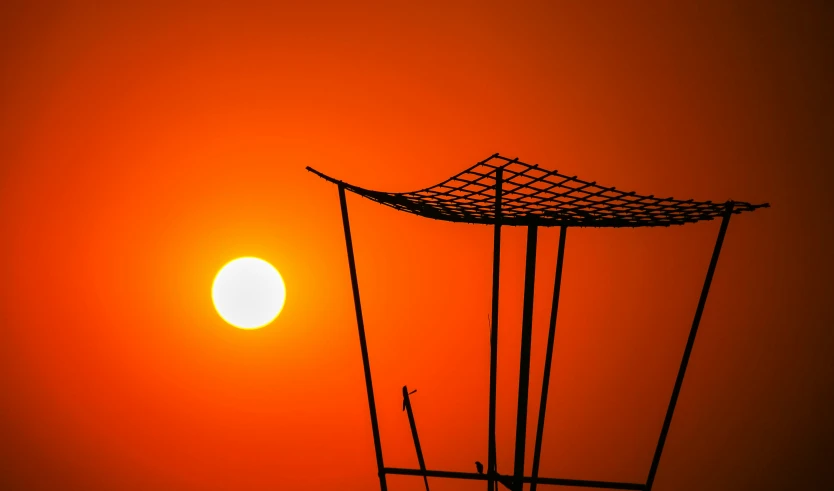 the sun setting behind the metal structures in front of a sky