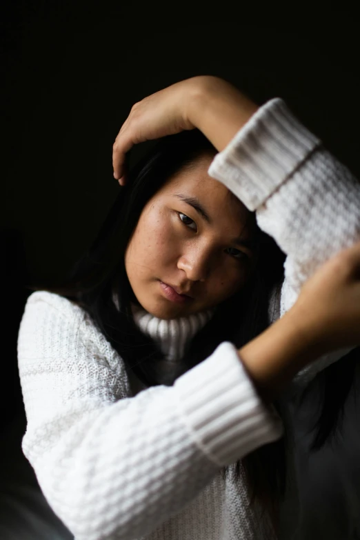 an asian woman with her hand on her head and hair falling