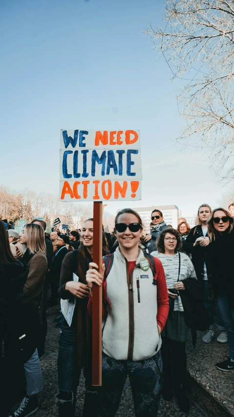 a man standing holding a sign that says we need ultimate action