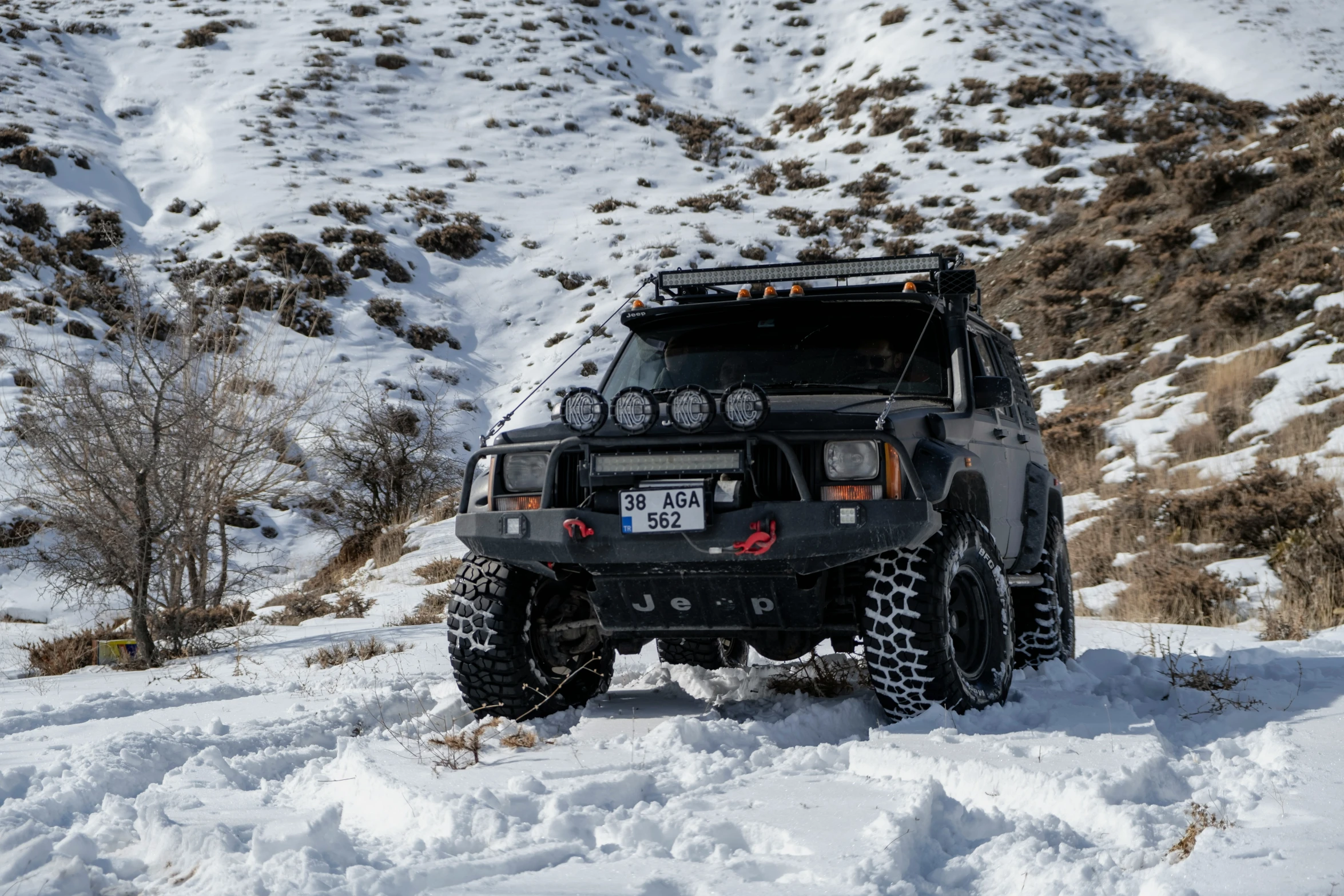 a jeep driving on a snowy road with lots of stuff