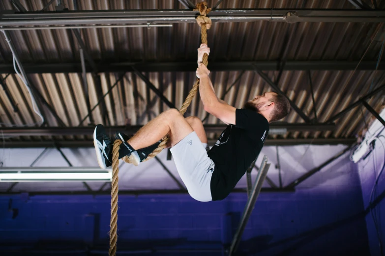 a man is hanging upside down on ropes