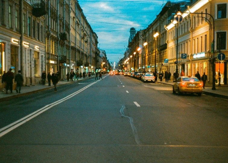 a dark city street at night with cars parked on both sides