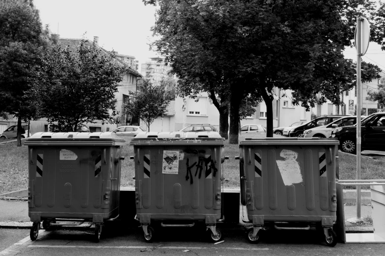 three dumpsters with garbage cans in front of them