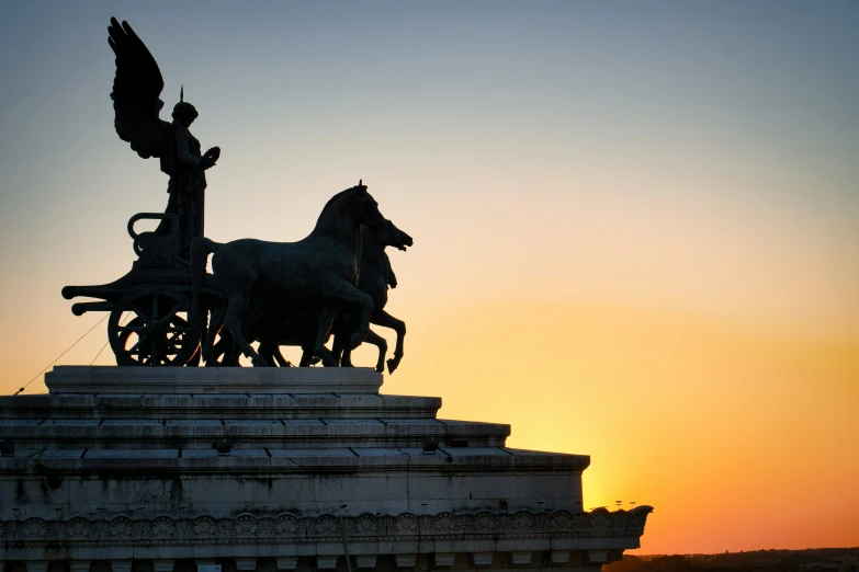 a statue of a horse drawn carriage in front of a sunset