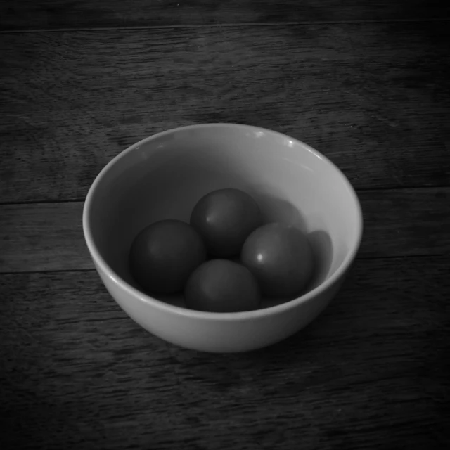 a bowl filled with balls sitting on a wooden floor