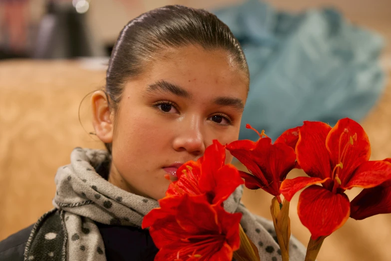 a girl is holding two red flowers in her hand