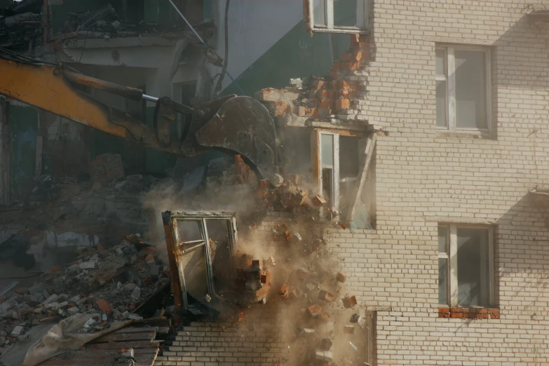 a demolition crew working on the back side of a brick building