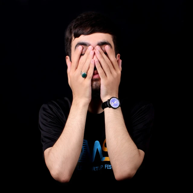 a man with his hands covering his face in front of him