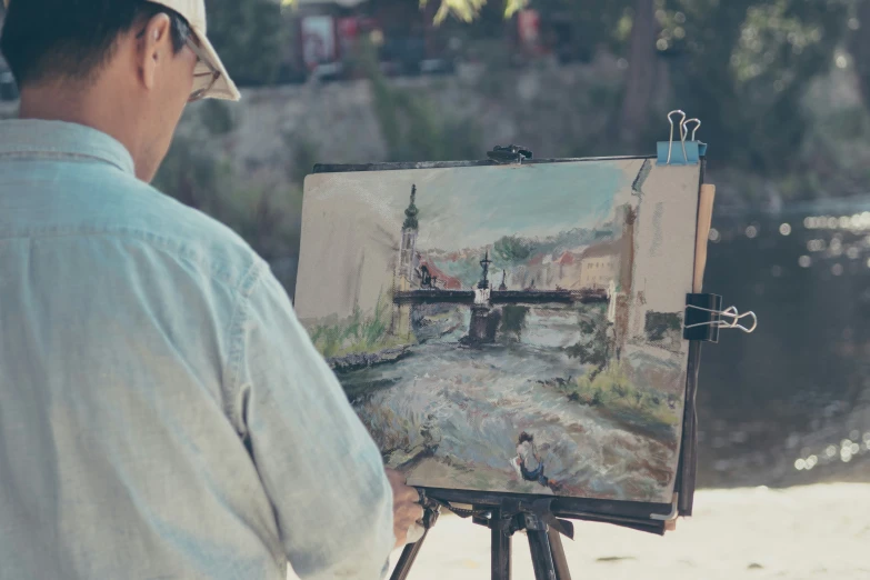 a man sitting in front of a painting next to a river