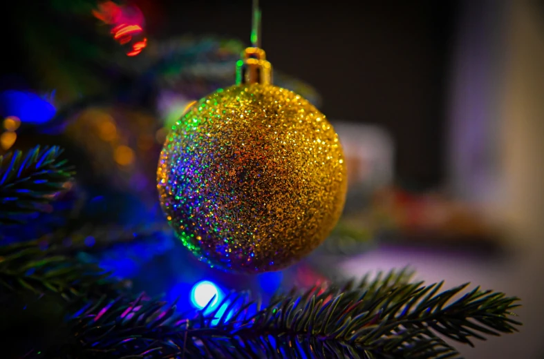 a bright christmas ornament on a tree with colored lights