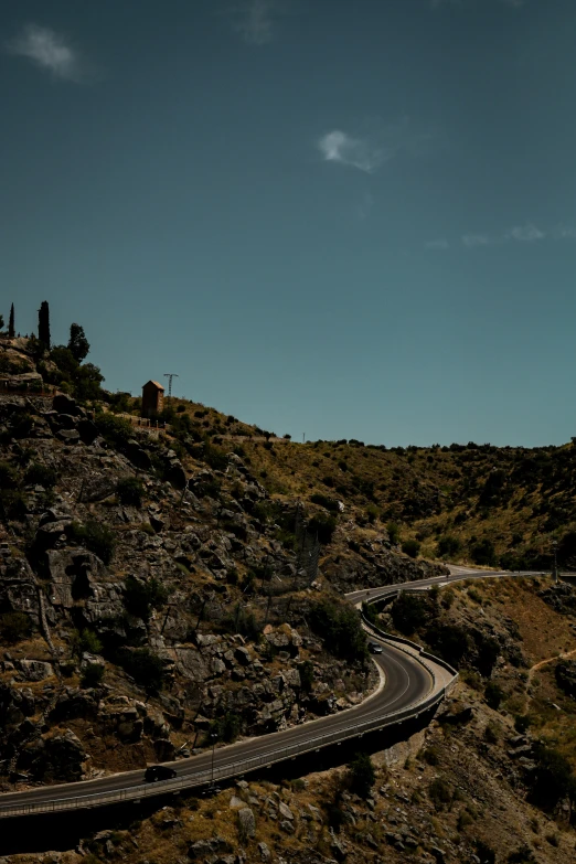 a winding road going to a small cabin on the mountain