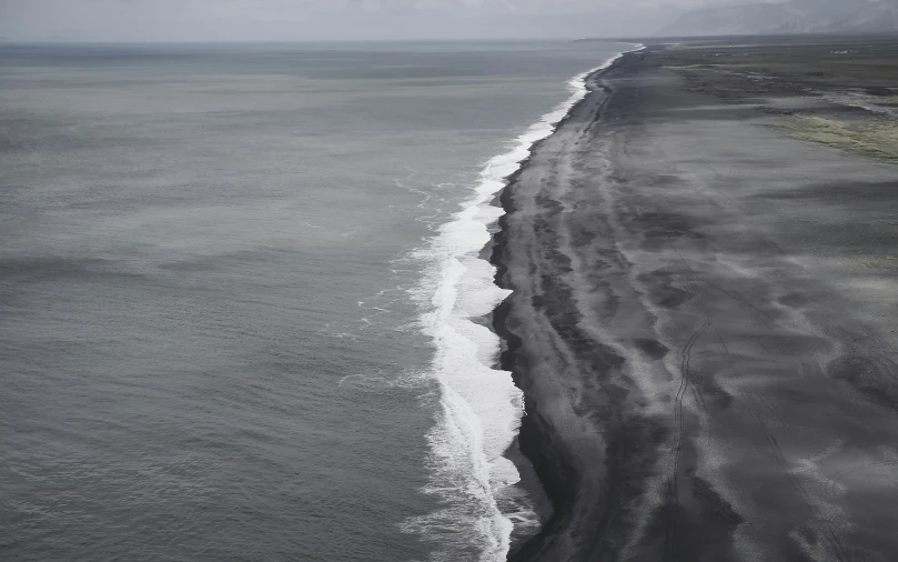 view of black and white landscape with surf and ocean