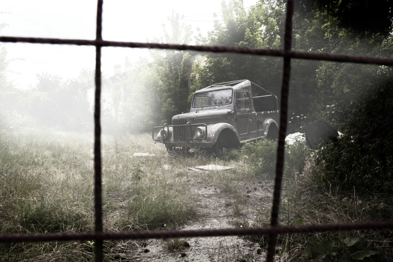 an old truck sitting behind a fence on a path