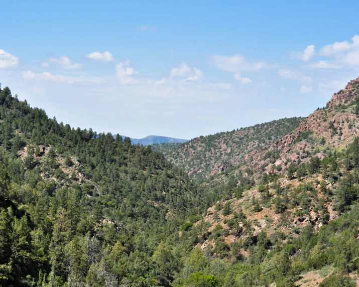 green mountains are shown with white clouds in the sky