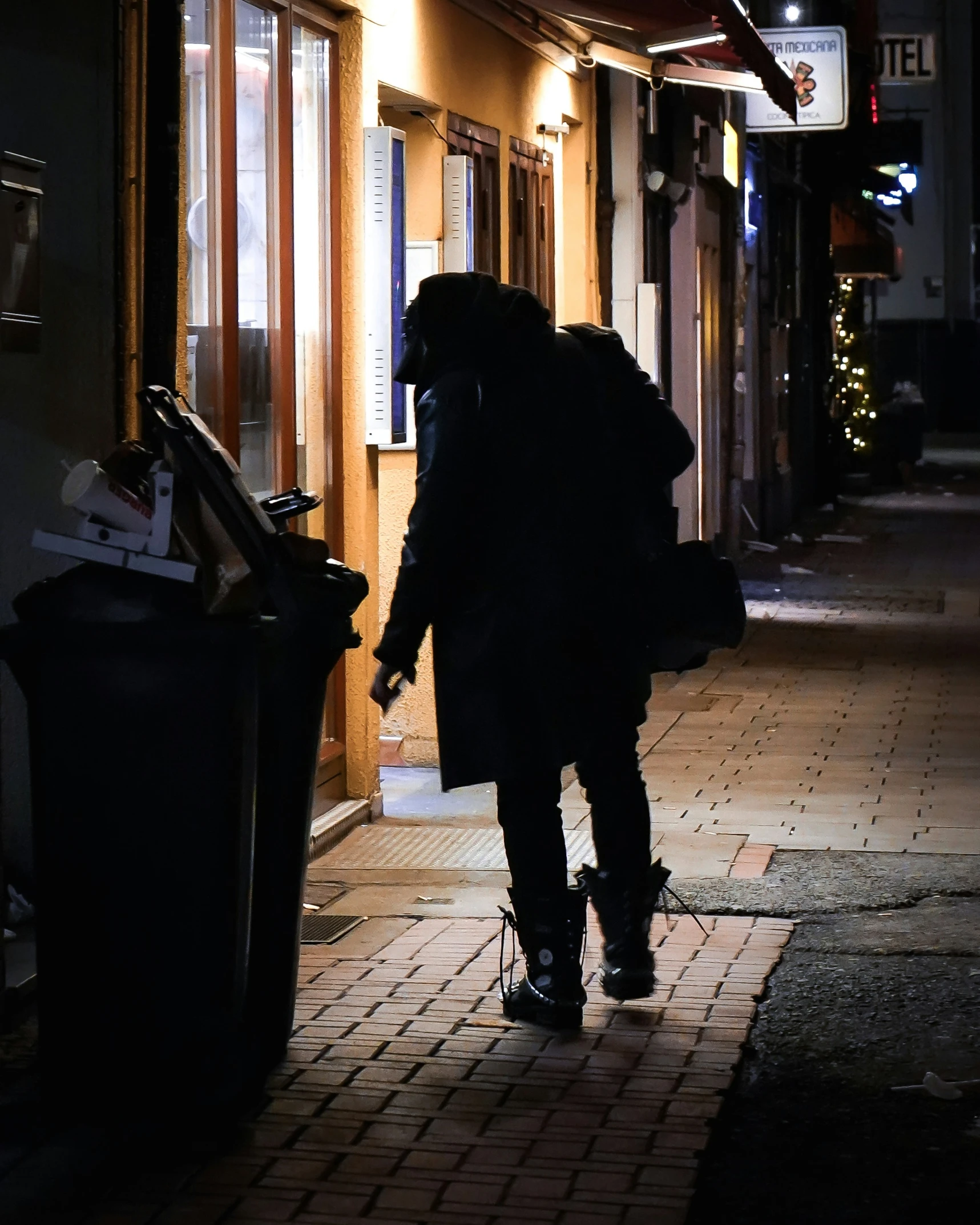 the man is walking along the street at night