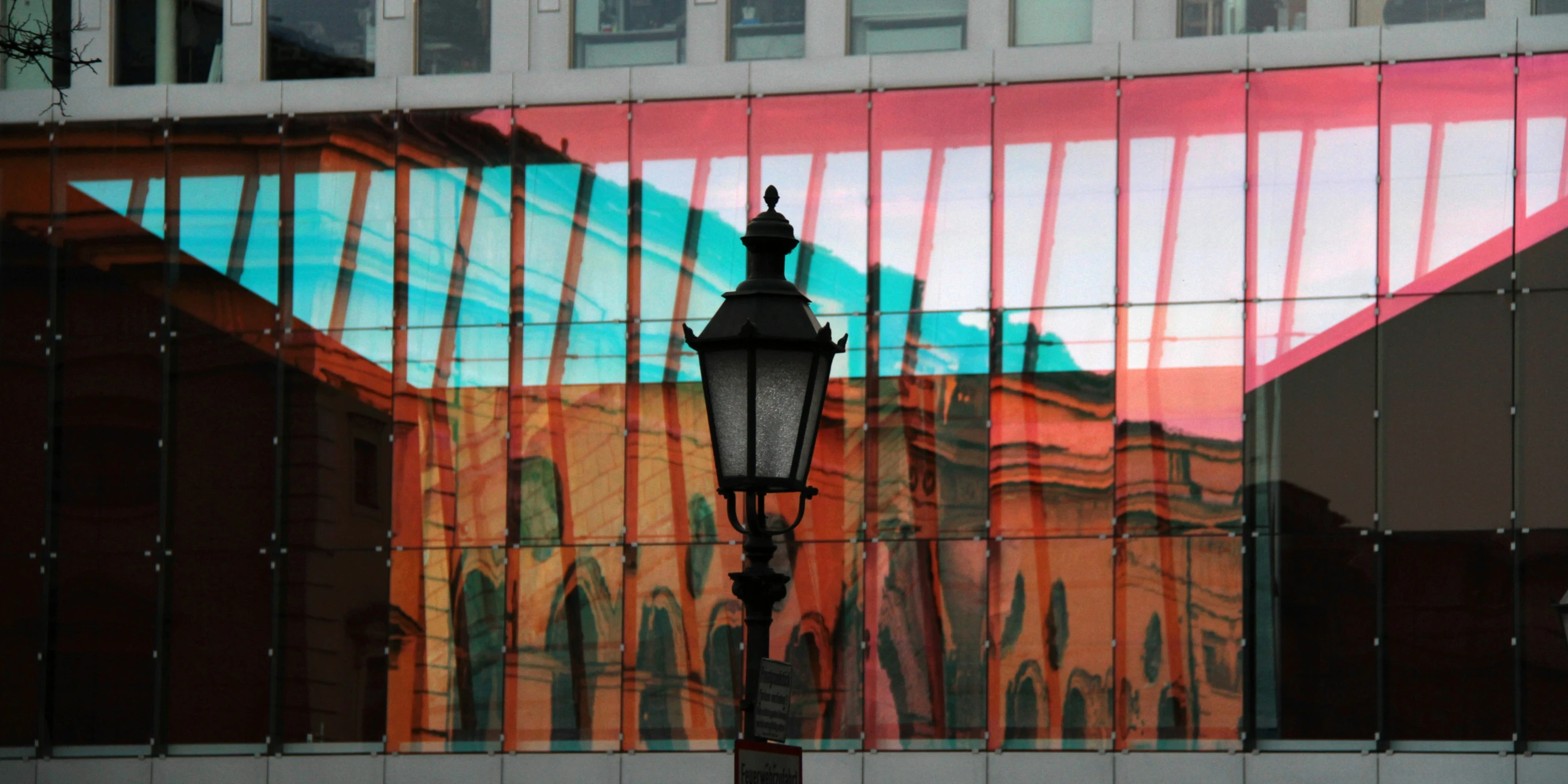 an orange building reflects in a glass window