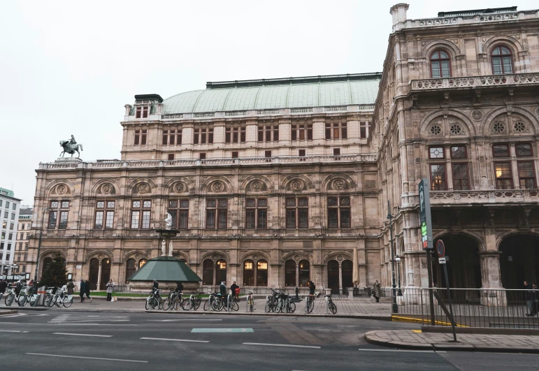 people riding bicycles outside a large building in the city