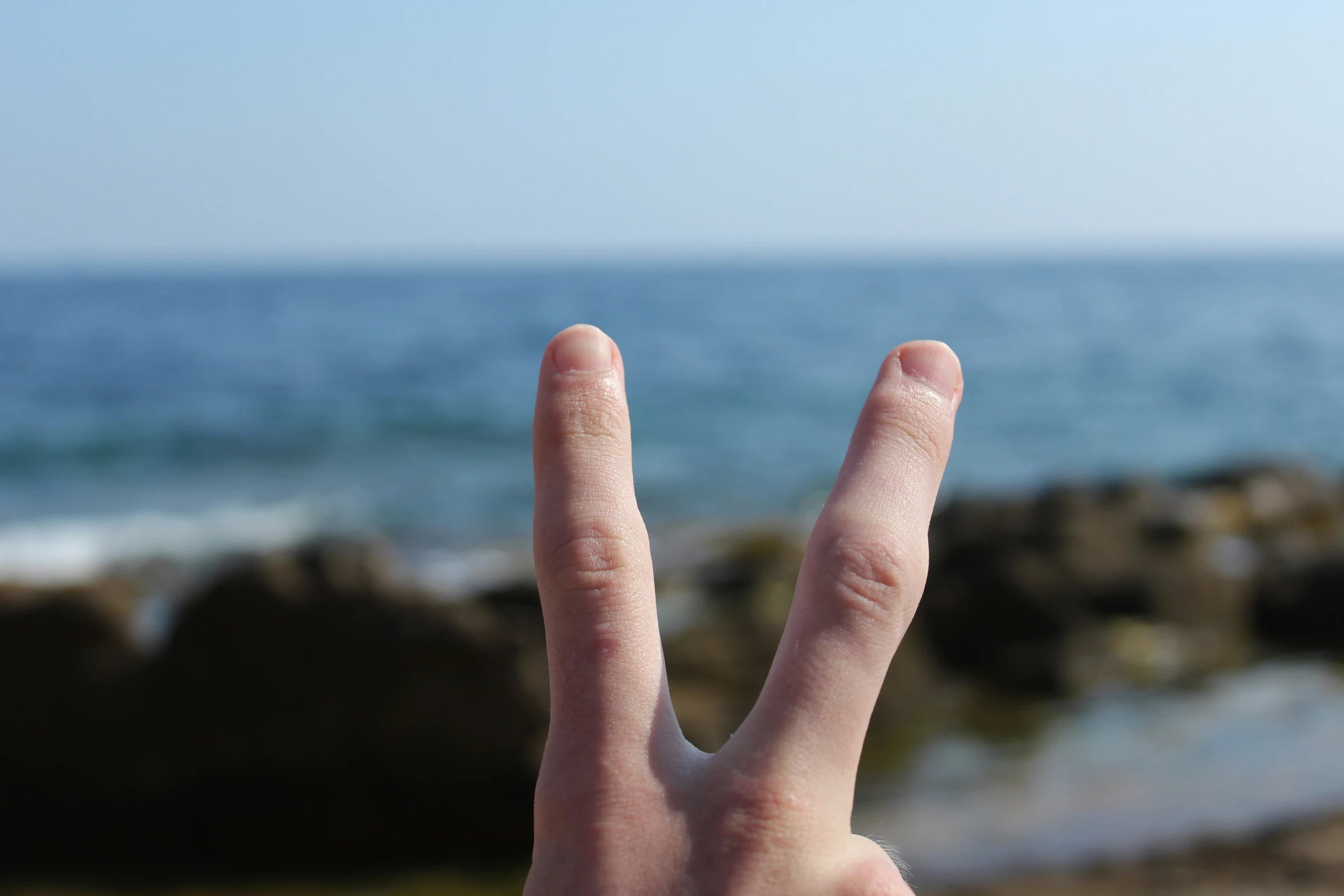 the person is holding up his hand in front of an ocean