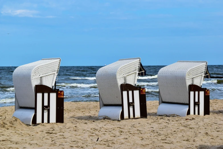 three sculptures are placed in the sand on a beach