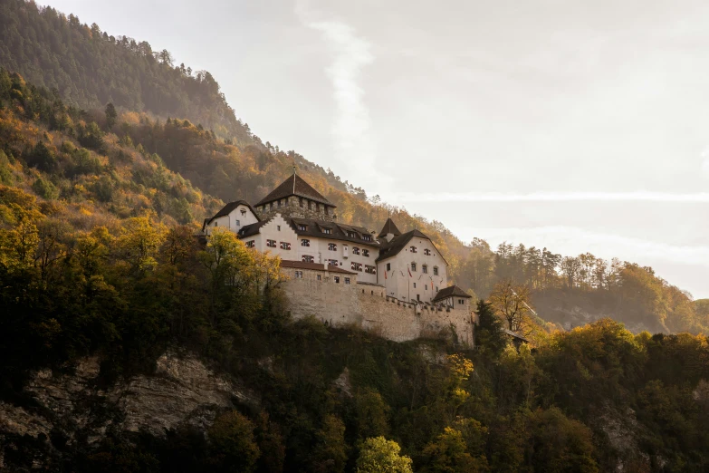 an old building sitting on the side of a hill with lots of trees