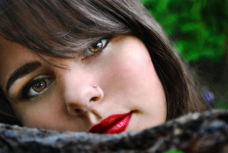 woman with red lips and nose piercing, her nose looking straight into camera