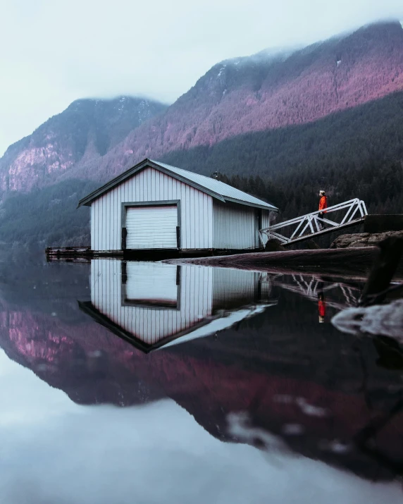 man walking into the water by a small shack