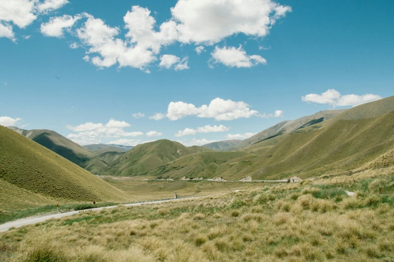 the sky is bright and fluffy over the rolling hills