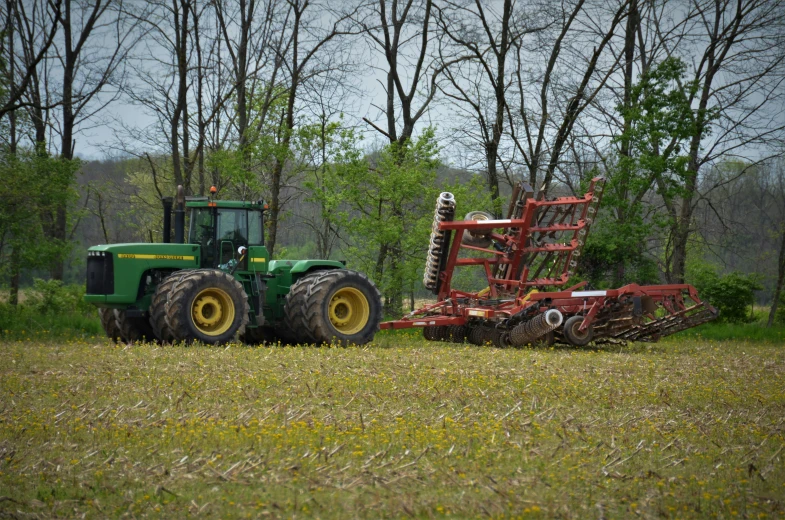 a tractor and plow moving across a grassy field