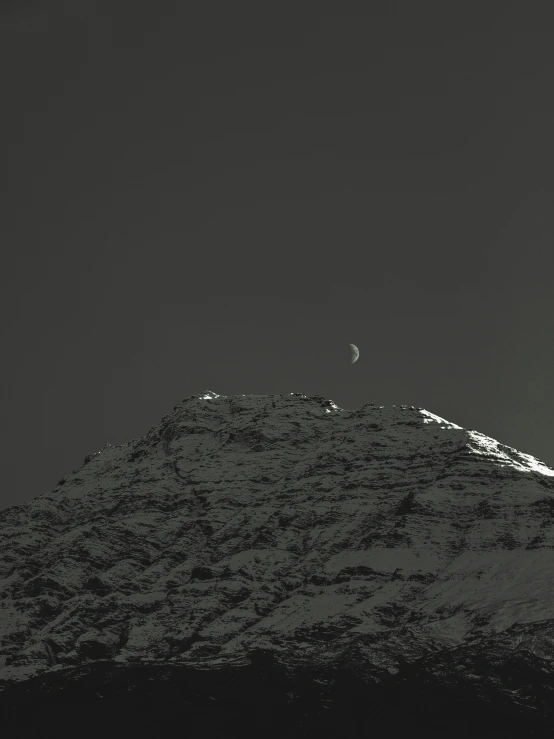 the moon is setting at the top of the mountain