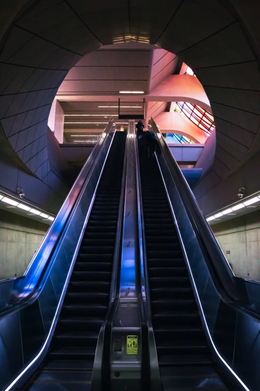 a blue escalator going through an underground terminal