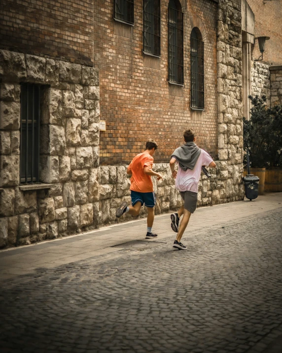 the two people are running on the cobblestone street