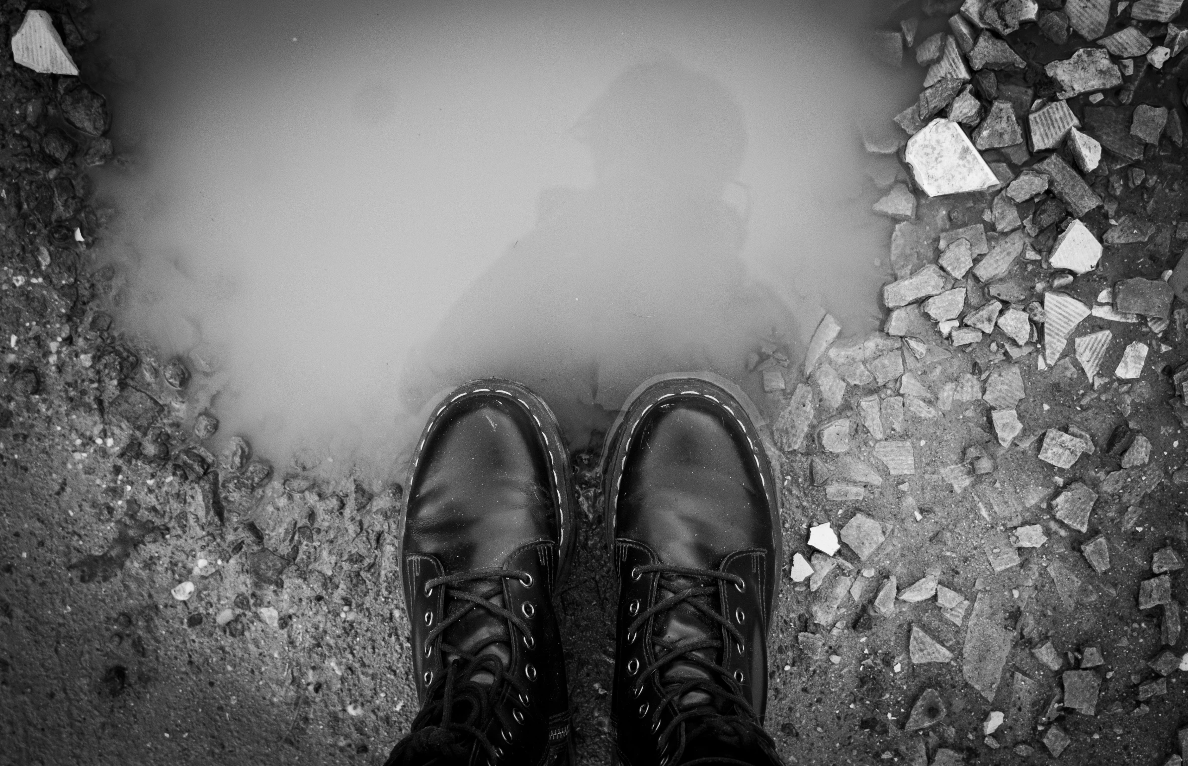 a man's legs and a pair of black shoes stand on a cobblestone floor