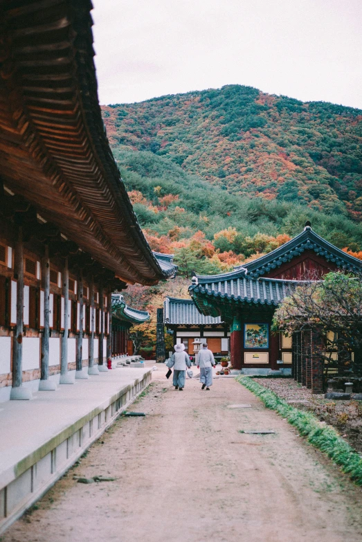 two people walking in the shade by a temple