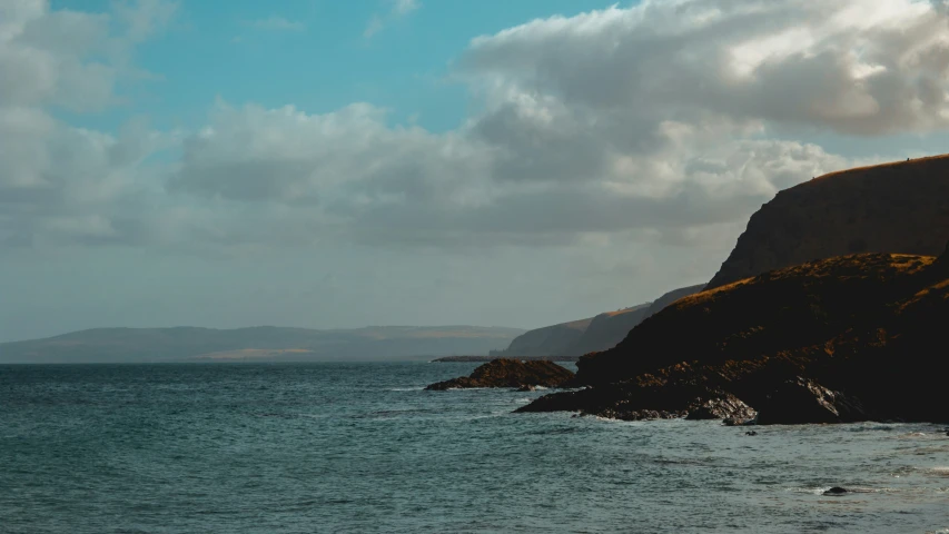 a boat sailing on the ocean near a rocky cliff