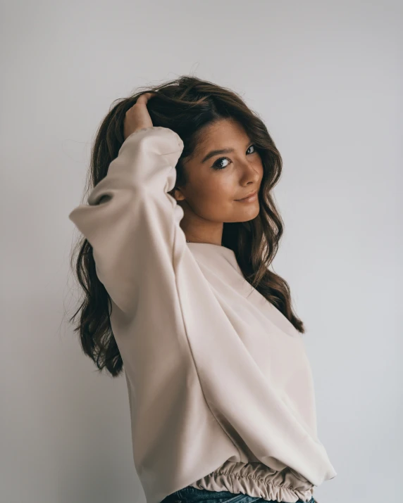 a woman is posing for a po, dressed up and wearing jeans and a top