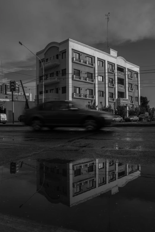 black and white image of a car passing by building