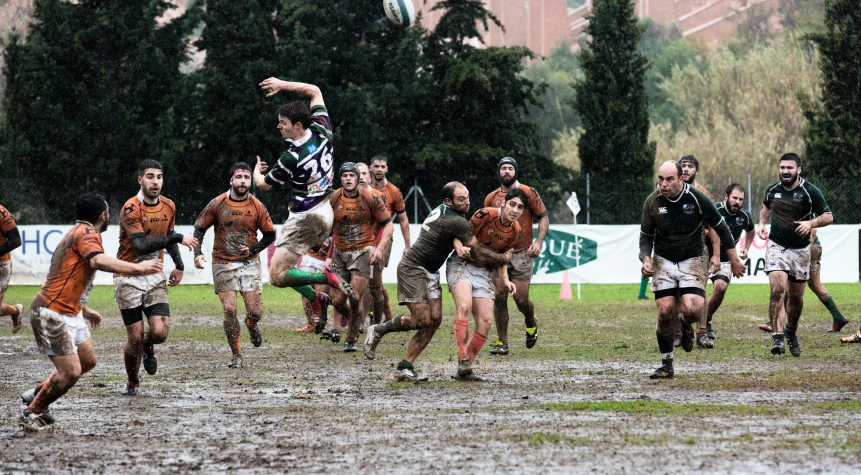 men are running and playing rugby on the muddy ground