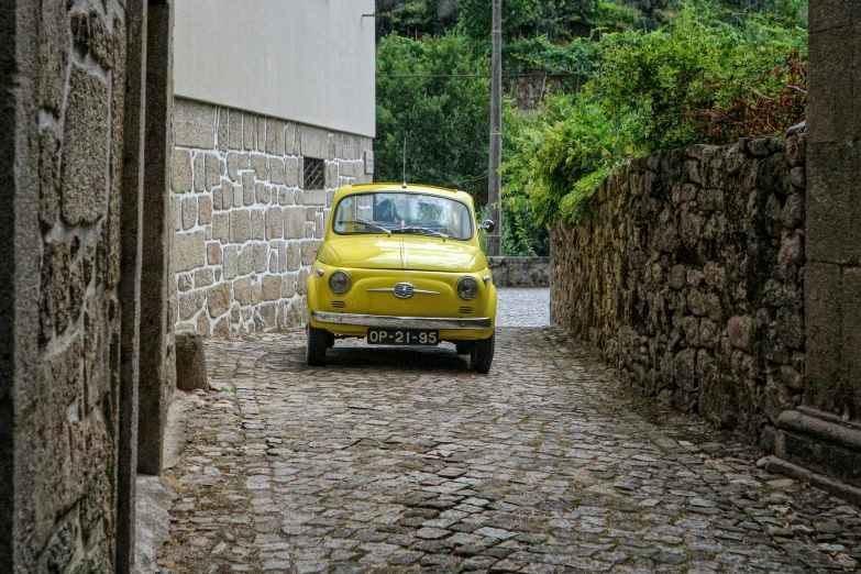 a small yellow car is parked on cobblestone