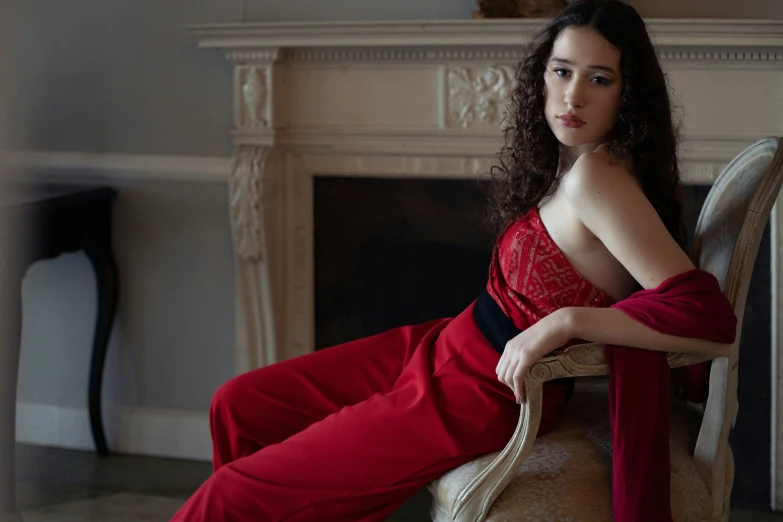 a woman sitting in a chair wearing a long red dress