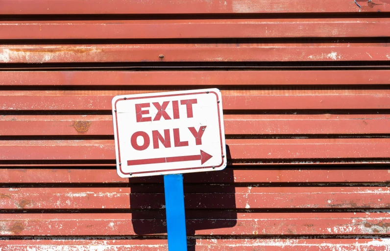 a blue pole is near a sign that says exit only