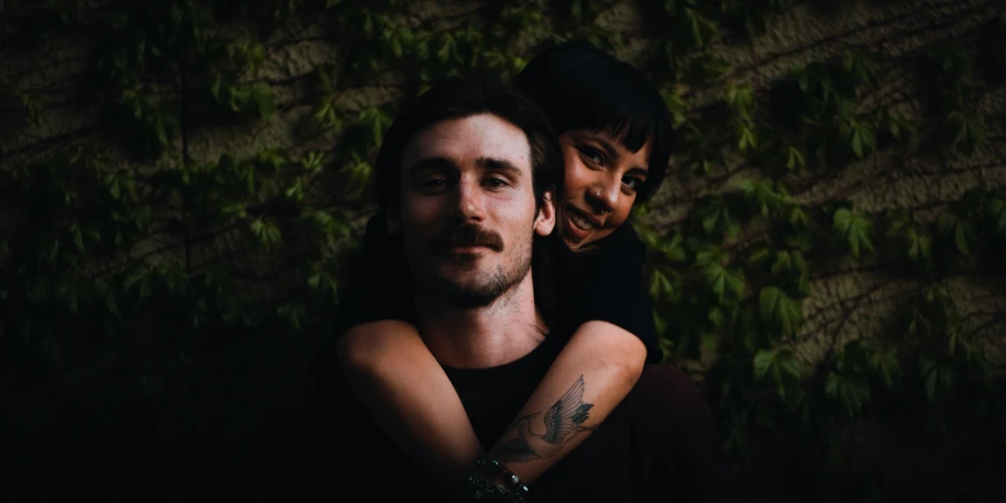 a young man and woman are smiling while sitting next to a wall