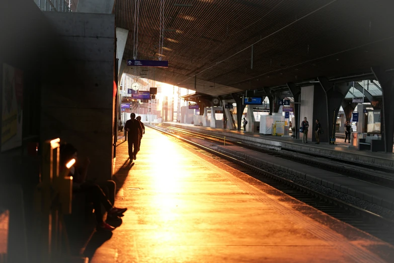 people walking away from train station platform at sunset