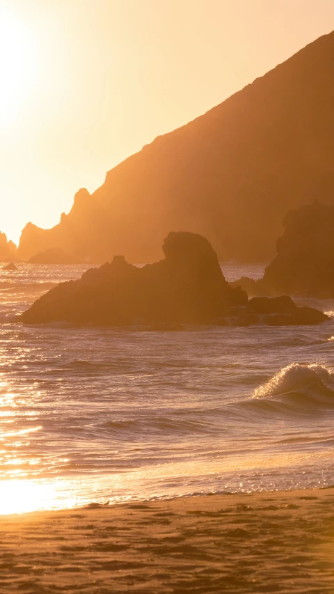 a beach area with a sunset and rocks