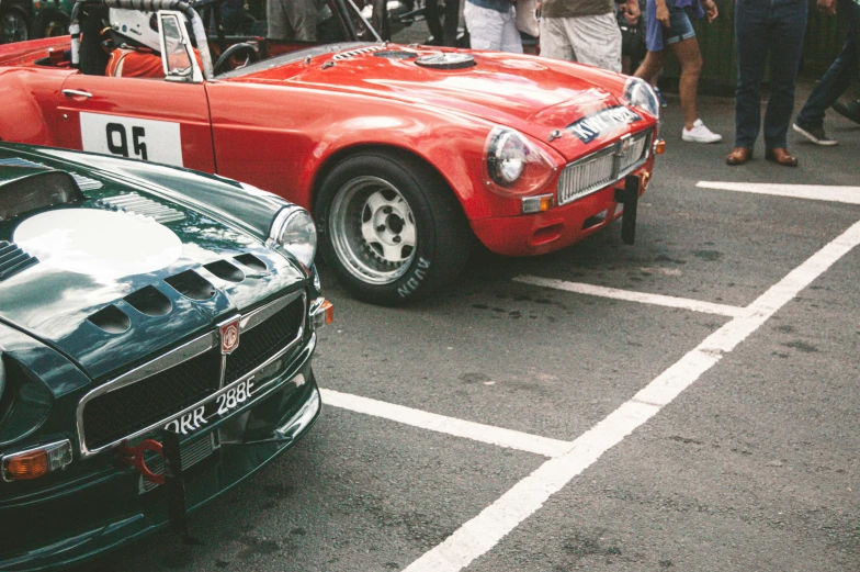 people standing around a group of cars parked next to each other