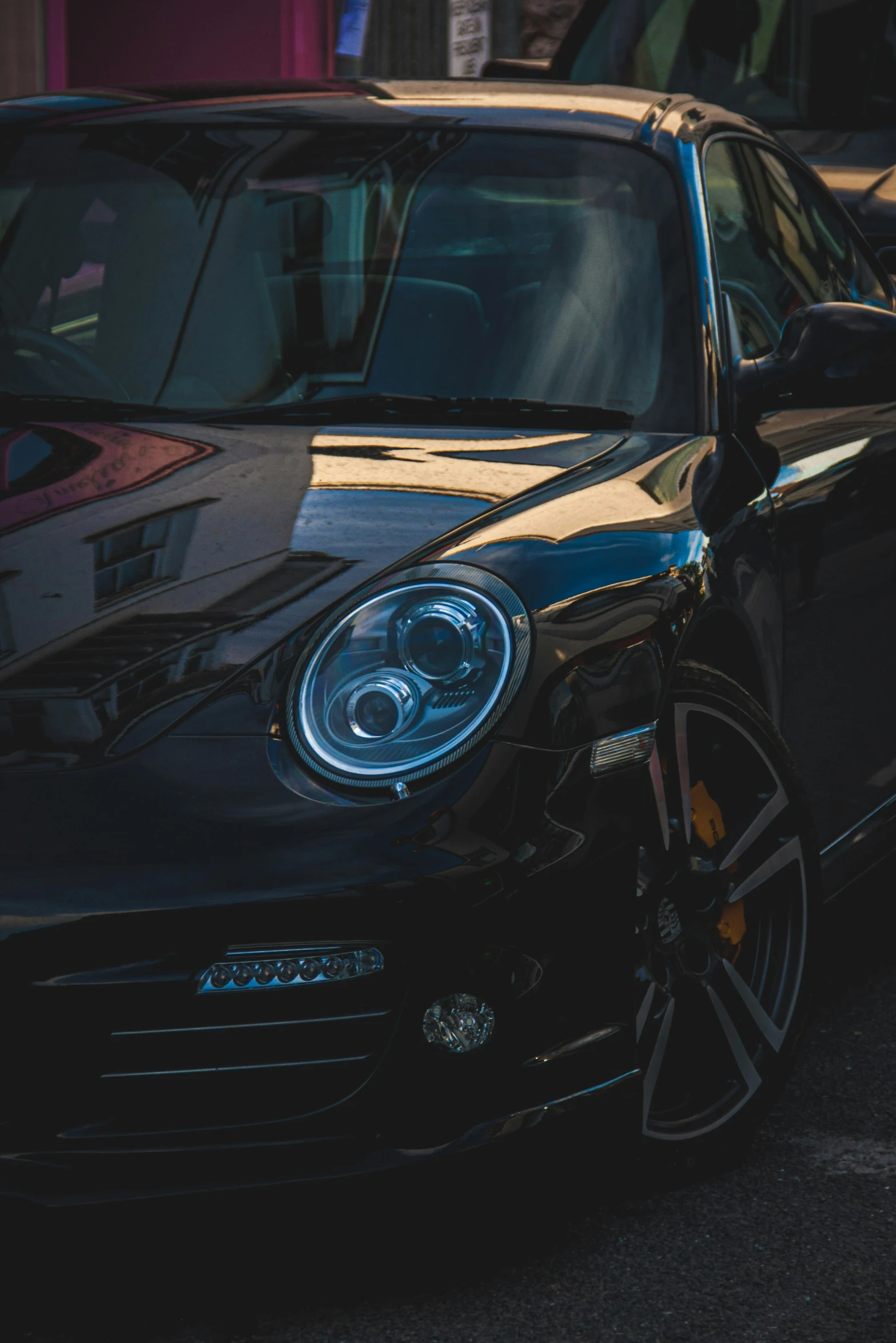 a black porsche parked in the street next to another car